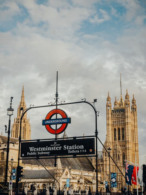 View of Westminster Underground Station entrance with the iconic London Underground roundel sign, situated in Westminster near Victoria Station. The scene includes a paved sidewalk with several pedest